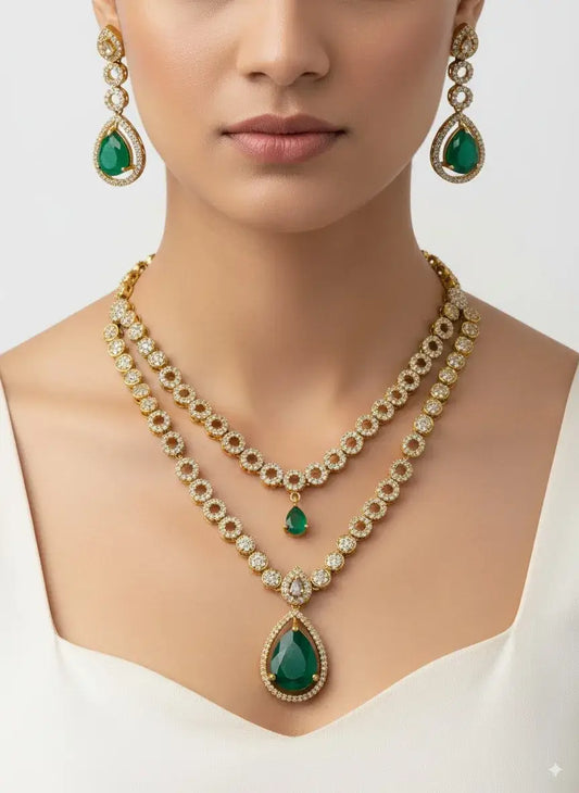 Woman wearing a gold necklace and earrings with green gemstones on a white background