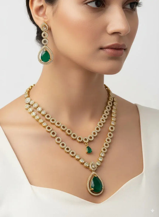 Woman wearing a gold necklace with green gemstones and matching earrings on a white background