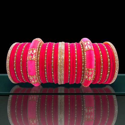Stack of pink bangles with gold accents on a reflective surface