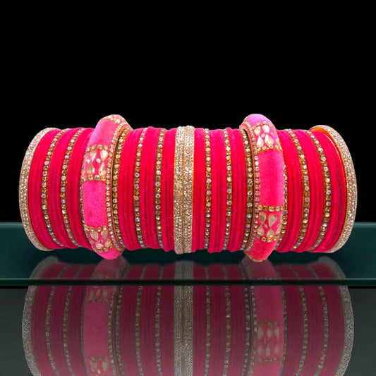 Stack of pink bangles with gold accents on a reflective surface
